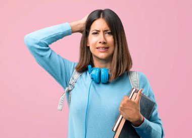 Mavi kazak ve kulaklık ile genç öğrenci kız pembe arka plan üzerinde migren çünkü kafasına el ele alır