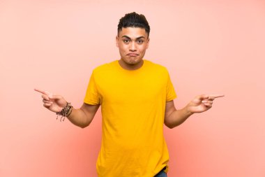 Izole pembe duvar üzerinde sarı gömlekli genç adam şüpheleri olan lateraller işaret