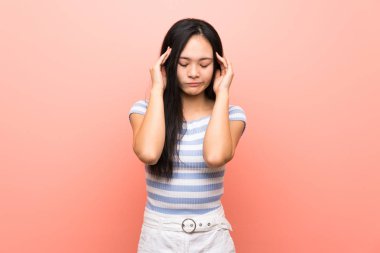 Baş ağrısı ile izole pembe arka plan üzerinde Genç asya kız