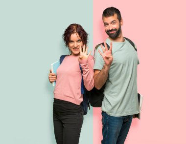 Sırt çantaları ve kitapları mutlu ve renkli duvarda parmakları ile dört sayma ile iki öğrenci