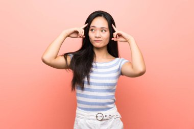 Şüphe ve düşünme sahip izole pembe arka plan üzerinde Genç asya kız