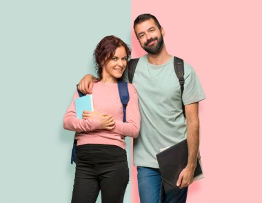 Renkli duvarda sırt çantaları ve kitaplar ile Mutlu iki öğrenci