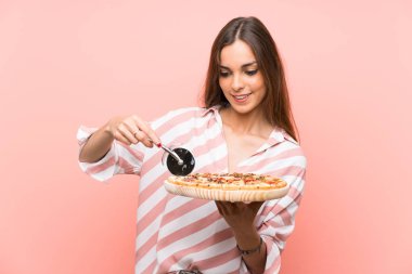 İzole pembe duvar üzerinde pizza tutan genç kadın