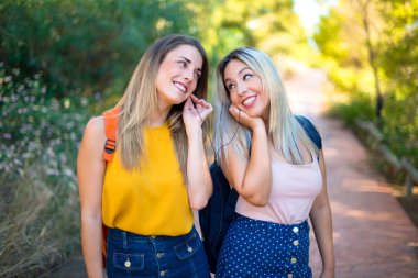 Bir parkta müzik dinleyen sırt çantası ile genç öğrenci kızlar