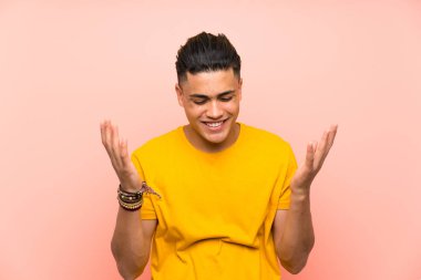Izole pembe duvar üzerinde sarı gömlekli genç adam gülüyor