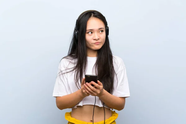 Tiener Aziatische Meisje Luisteren Muziek Geïsoleerde Blauwe Muur — Stockfoto