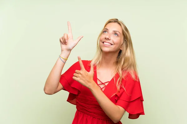 Blonďatá Mladá Žena Izolované Zelené Pozadí Ukazující Prstem Ukazováček Skvělý — Stock fotografie