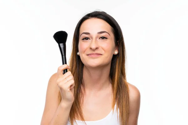 Mujer joven sosteniendo una gran cantidad de cepillo de maquillaje sobre fondo blanco aislado — Foto de Stock