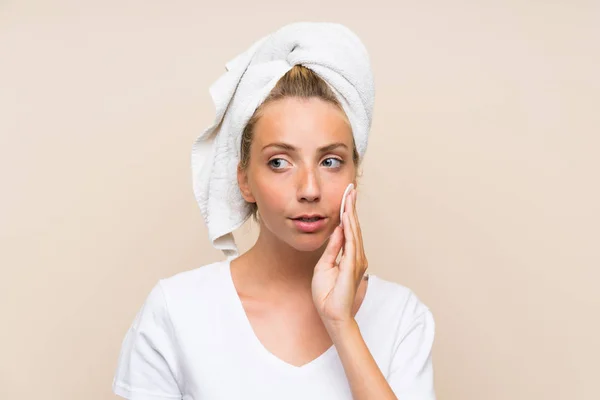 Young blonde woman removing makeup from her face with cotton pad — Stock Photo, Image