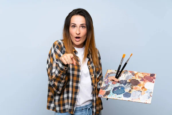 Joven Pintora Mujer Sobre Aislado Fondo Azul Sorprendido Apuntando Frente — Foto de Stock