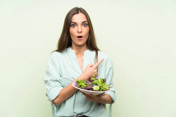 Junge Frau Mit Salat Über Isolierte Grüne Wand Überrascht Und — Stockfoto