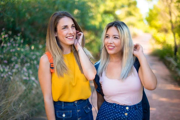 Bir parkta müzik dinleyen sırt çantası ile genç öğrenci kızlar