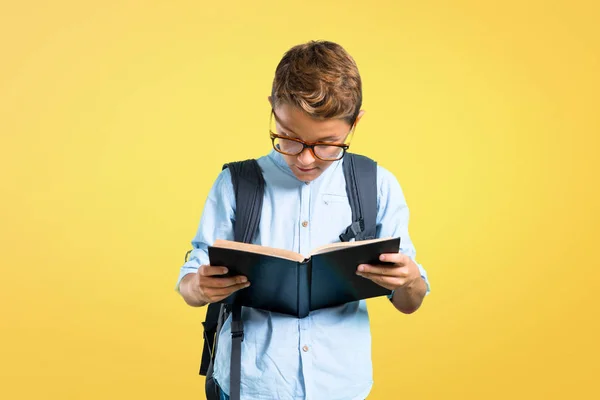 Niño Estudiante Con Mochila Gafas Sosteniendo Libro Sobre Fondo Amarillo —  Fotos de Stock