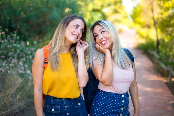 Bir parkta müzik dinleyen sırt çantası ile genç öğrenci kızlar