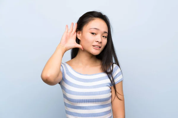Adolescente Asiático Menina Sobre Isolado Azul Fundo Ouvir Algo — Fotografia de Stock
