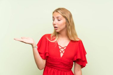 Avuç üzerinde copyspace hayali tutan izole yeşil arka plan üzerinde Sarışın genç kadın