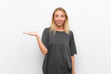 Bir reklam eklemek için avuç üzerinde copyspace hayali tutan izole beyaz arka plan üzerinde Blonde genç kadın