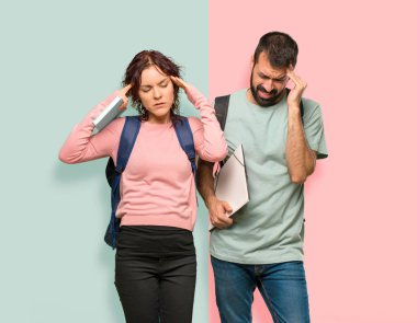 Sırt çantaları ve kitapları olan iki öğrenci bir şeyden memnun değil. Renkli duvarda negatif yüz ifadesi