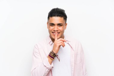 Izole beyaz duvar üzerinde sessizlik jesti yapan genç adam