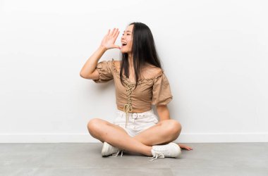 Genç asyalı kız ağız ardıardı ile bağırarak yerde oturan