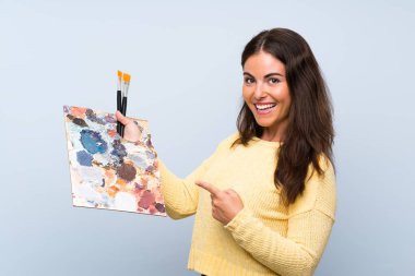 Izole mavi arka plan üzerinde genç sanatçı kadın ve işaret