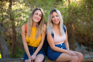 Bir parkta müzik dinleyen sırt çantası ile genç öğrenci kızlar