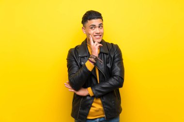 Izole sarı arka plan üzerinde genç adam bakarken bir fikir düşünme