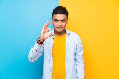 Parmakları ile ok işareti gösteren izole renkli arka plan üzerinde genç adam