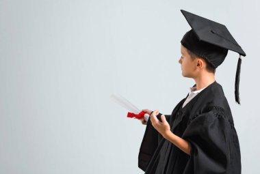 Küçük çocuk gri arka plan üzerinde işaret parmağı ile geri işaret mezun