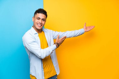 Izole renkli arka plan üzerinde genç adam gelmeye davet için yan ellerini uzatan