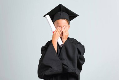 Küçük çocuk gri arka plan üzerinde elleri ile gözleri kaplayan mezun