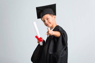 Küçük çocuk gri arka planda size puan parmak mezun