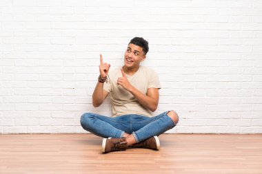 Genç adam yere oturup işaret parmağıyla işaret etmek harika bir fikir.