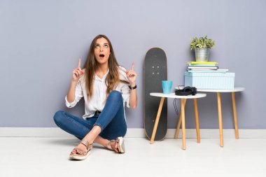 Yerde oturan genç bayan işaret parmağıyla işaret etmek harika bir fikir.