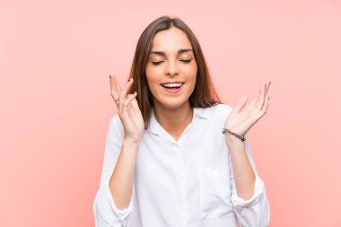 Genç bir kadın pembe arka planda gülüyor.