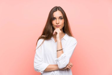 Genç bir kadın pembe arka planda gülüyor.