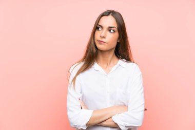 Soyutlanmış pembe arka planı olan genç bir kadın bir fikir düşünüyor.