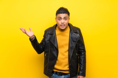 Izole sarı arka plan üzerinde genç adam şüphe jest yapma