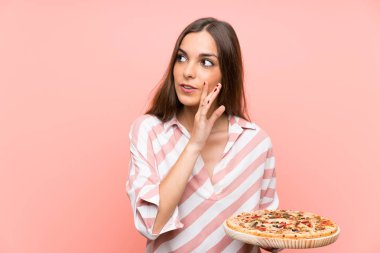 İzole edilmiş pembe duvarın üzerinde pizza tutan genç kadın bir şeyler fısıldıyor