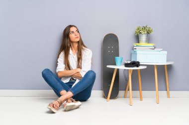 Genç bir kadın yerde oturmuş bir fikir düşünüyor.