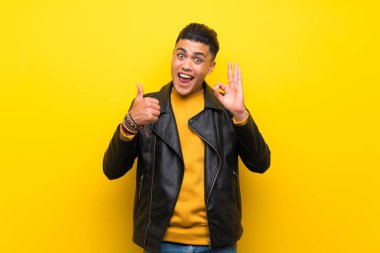 Izole sarı arka plan üzerinde ok işareti ve başparmak yukarı jest gösteren genç adam
