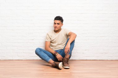 Genç adam şüpheler ve karışık yüz ifadesi ile katta oturan