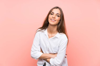 Genç bir kadın pembe arka planda gülüyor.