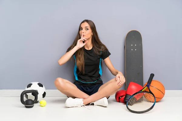 沈黙のジェスチャーをして床に座っている若いスポーツ女性 — ストック写真