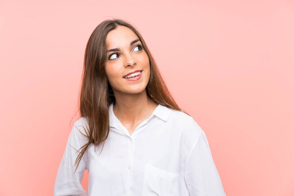 Молодая женщина на изолированном розовом фоне смеется и смотрит вверх
