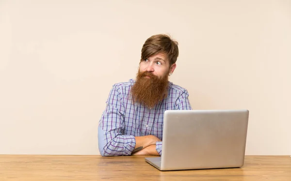 Homem Ruivo Com Barba Longa Uma Mesa Com Laptop Olhando — Fotografia de Stock