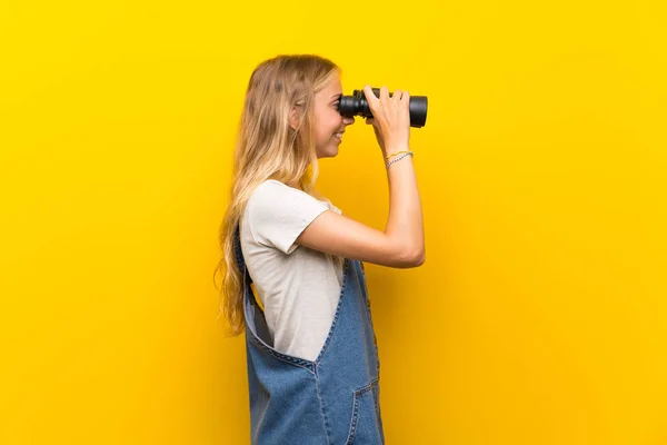 Jovem Loira Sobre Fundo Amarelo Isolado Com Binóculos Pretos — Fotografia de Stock