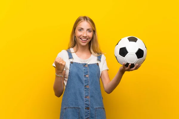 Loira Jovem Sobre Isolado Fundo Amarelo Segurando Uma Bola Futebol — Fotografia de Stock