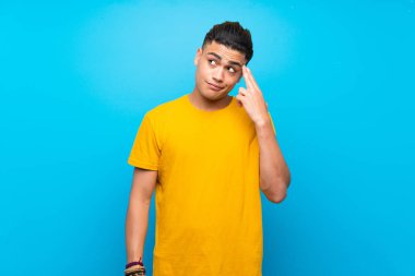 İntihar jesti yaparken sorunlar ile izole mavi arka plan üzerinde sarı gömlekli genç adam