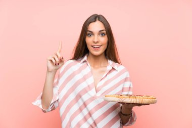Genç kadın izole pembe duvar üzerinde bir pizza tutan harika bir fikir işaret